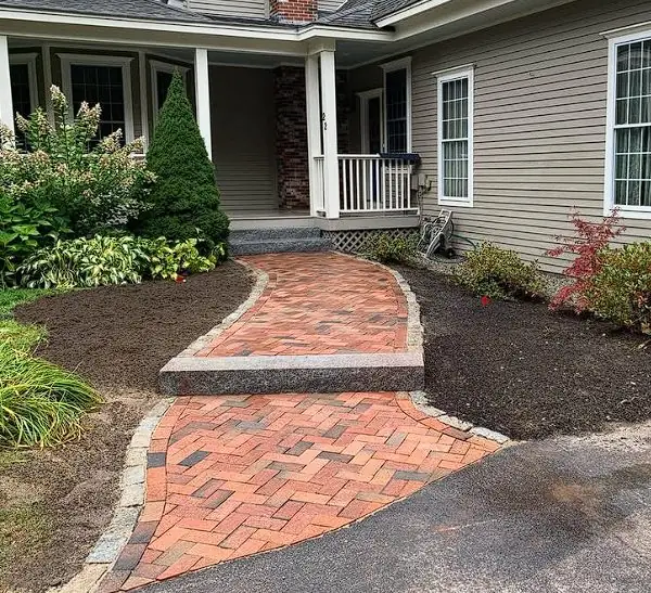Curved brick paver walkway leading to a home entry in Maine