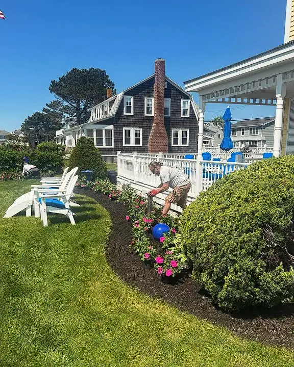 Landscaped coastal Maine home with foundation plantings and Adirondack chairs