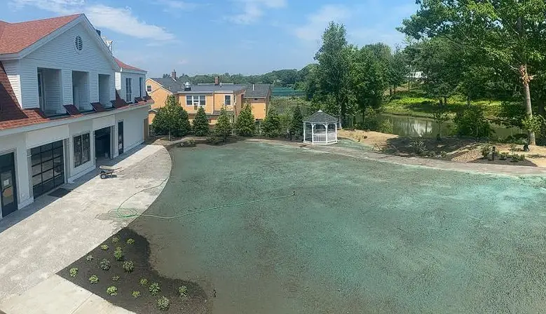 Aerial view of commercial hydroseeding around a pool and parking area in Maine