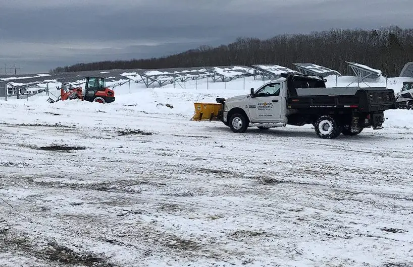 Commercial snow removal with a dump truck on a winter job site in Maine