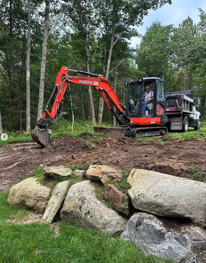 Mini excavator placing boulders for a retaining wall project