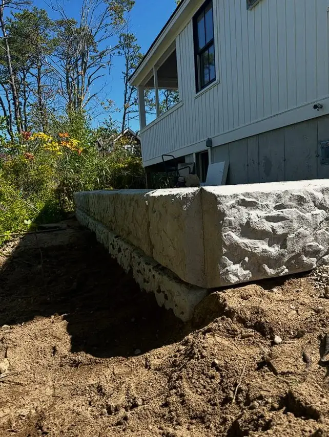 Foundation retaining wall excavation and stonework in progress