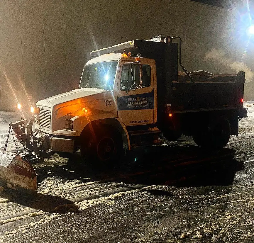 Dump truck plowing snow at night for Billy Goat Landscaping