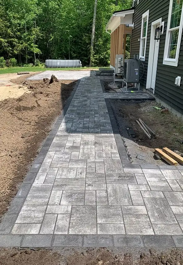 Paver walkway installation in progress next to a Maine home