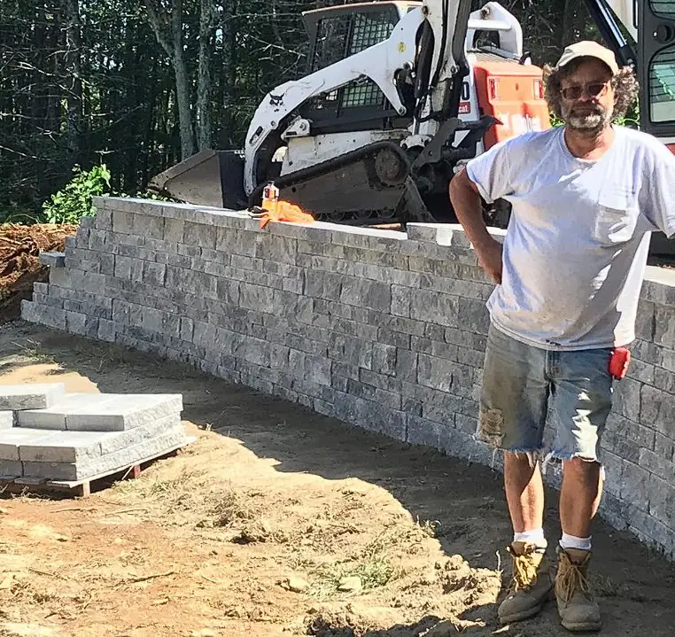 Billy Goat Landscaping crew member building a natural stone retaining wall